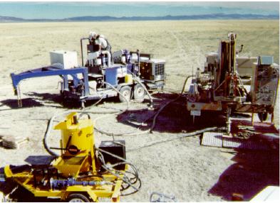 LANL coiled-tubing microdrilling rig (right), with mud cleaning system (rear left) and contract grout/cement mixer (front) on location at demonstration site