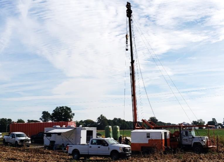 Rexing #4 well head in September 2018. A workover rig, the mobile laboratory, and a frac tank filled with 100 bbl of fresh water were on site during the field work.