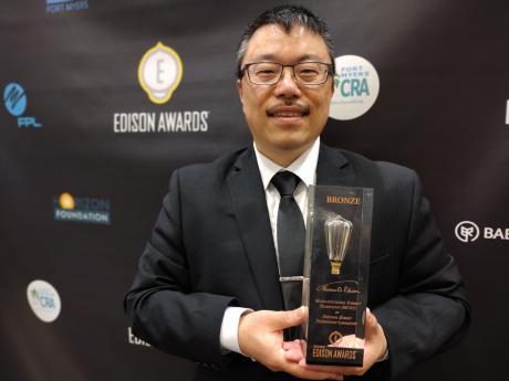NETL's Fan Shi holding a bronze Edison Award