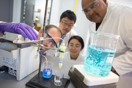 Four scientists looking at a test tube in a lab,