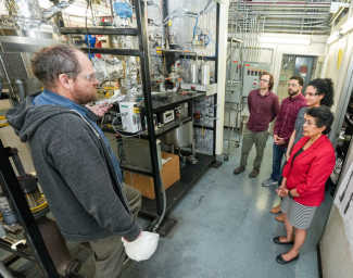 NETL researchers Michael Bobek (left), Ranjani Siriwardane (right front), Hayat Adawi (right), Chris Atallah (right middle) and Jarret Riley (back) discuss their recent catalyst test. 